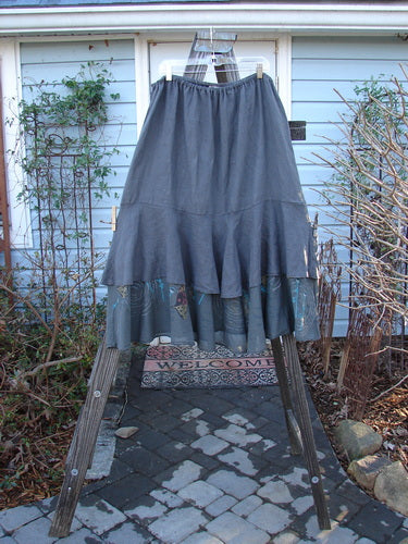Barclay Linen Two Tier Ruffle Skirt Angel Fish Storm Grey Size 2 displayed on a clothes rack, showcasing its flowing double A-line design and distinctive layered ruffles.