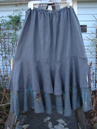 Barclay Linen Two Tier Ruffle Skirt Angel Fish Storm Grey Size 2 displayed on an outdoor swing, showcasing its flowing double-layered design with a wide ruffled hem and unique angelfish pattern.