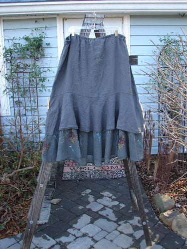 Barclay Linen Two Tier Ruffle Skirt Angel Fish Storm Grey Size 2 displayed on a clothes rack, highlighting its double-layered design with a wide ruffle hem and thin elastic waistband.