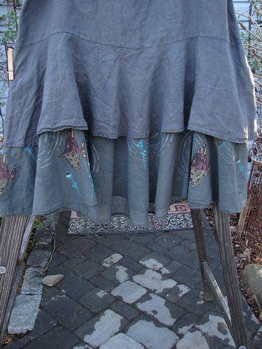 Barclay Linen Two Tier Ruffle Skirt Angel Fish Storm Grey Size 2 draped over a chair, showcasing its ruffled layers and detailed pattern, perfect for layering or wearing alone.