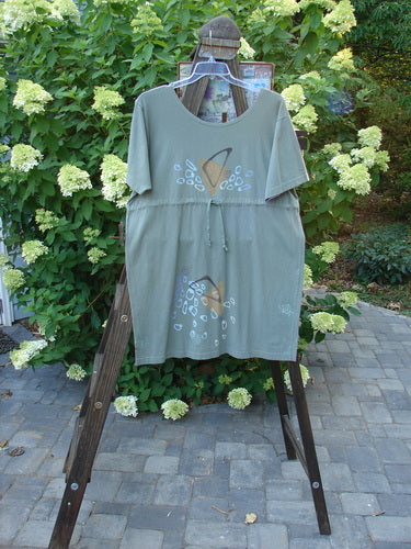 1996 Everyday Dress Step Stone Cricket Size 2 on a wooden rack, featuring a wide shape, drawcord accent, and stepping stone theme paint on lightweight organic cotton.