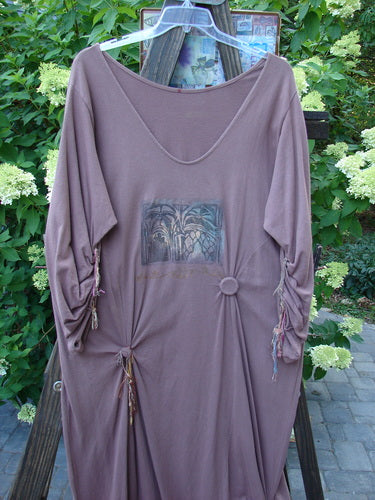 1994 Deep Neck Dress Embellished Forest Dusty Plum Size 2 on a wooden rack, showcasing sweet fish embellishments, added buttons with rippie ties, and a mix of silks and cotton ribbons.