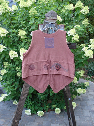 1995 Drawing Room Vest Windy Planet Clove OSFA: A vest on a rack, featuring a ceramic button front, tailored drawcord back, and a sweet front pocket. Made from reprocessed cotton, this medium spice vest is a timeless piece from Blue Fish Clothing's Fall Collection.