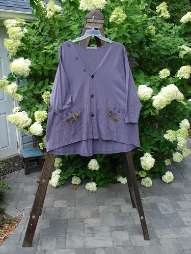 1996 Triangle Cardigan Garden Bug Purple Martin OSFA: A purple shirt with garden bug theme paint, featuring a deep V neckline, angled front pockets, and a varying hemline.