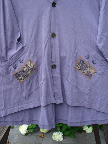 1996 Triangle Cardigan Garden Bug Purple Martin OSFA: close-up of deep V neckline, scooped hemline, angled front pockets, and original buttons with signature blue fish stamp on the lower back hem.
