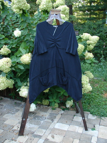 Barclay NWT Vector Tunic Dress Unpainted Black Size 2 displayed on a rack, showcasing its unique dip side hemline, V-shaped neckline, and exterior drop front pockets.