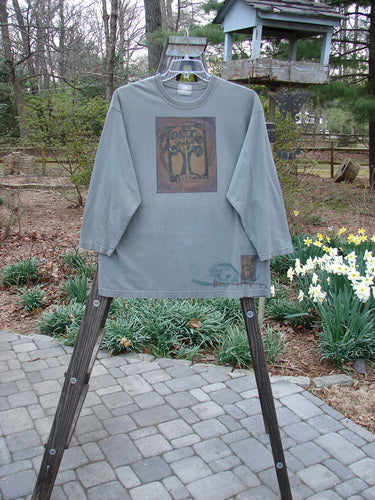 2000 Long Sleeved Tee Tree of Life Park Size 1 displayed on a wooden stand outdoors, showcasing its drop shoulders and colorful tree theme.