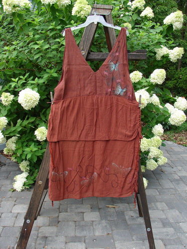 Barclay Gauze Linen Two Tier Ribbon Jumper Butterflies Cinnabar Size 1 displayed on a clothesline, highlighting its deep V neckline, lace-up bodice, and intricate silk ribbon shoulder ties.