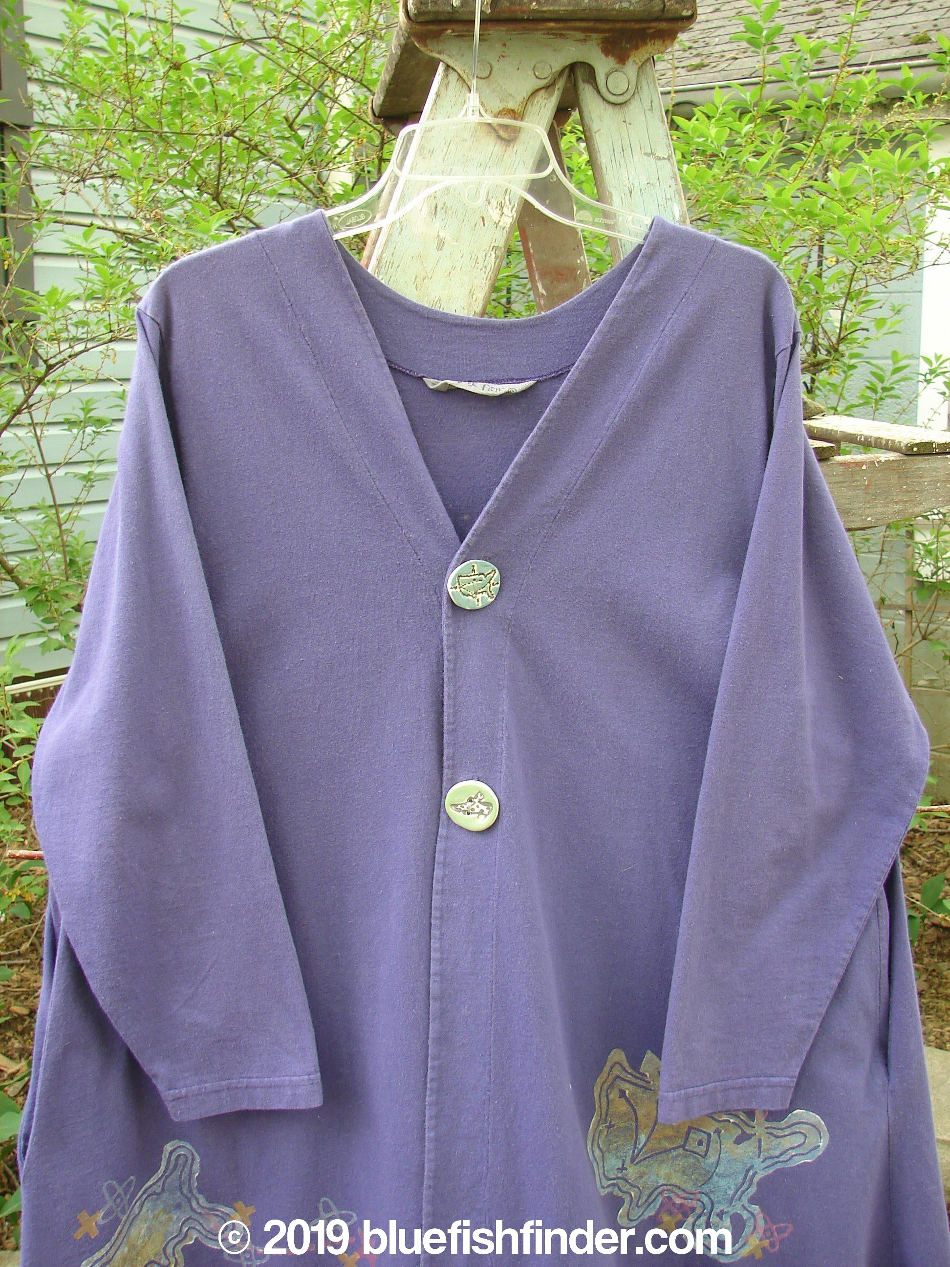 1996 Dining Car Jacket Travel Niagara Size 1: A purple shirt with buttons on a clothes rack. Features include a V-shaped neckline, artisan porcelain buttons, and deep side pockets.