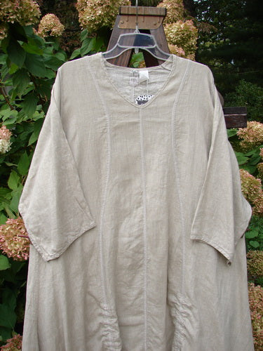 Barclay NWT Linen Shimmer Venetian Tunic Dress Unpainted Sand Shell Size 2 displayed on a hanger, showcasing its elongated shape, rounded V neckline, and pinched lower sleeves.