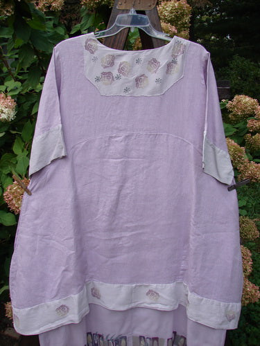Barclay Linen Crossover Two Tier Dress Floral Lavender Size 2 on a clothesline, showcasing its V-neckline, wide-cuffed sleeves, double-layered flow, and floral design.