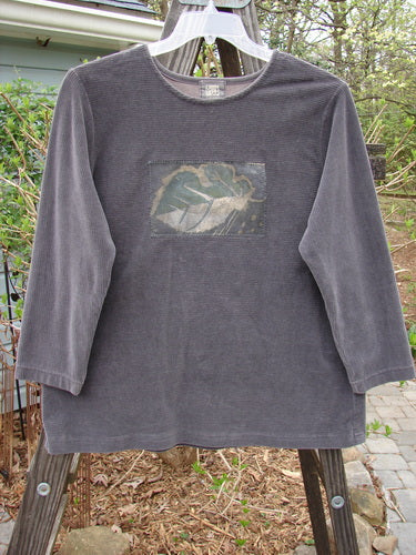 1999 Patched Stretch Cord Pullover Top Leaf Grey Plum Size 0: A grey shirt with a picture of a single leaf on it. Cozy and comfortable, made from stretch cotton corduroy. Features include vented sides, rounded neckline, drop shoulders, and slight A-line shape. Perfect condition with professional alteration. Bust 44, waist 44, hips 44, length 27 inches.