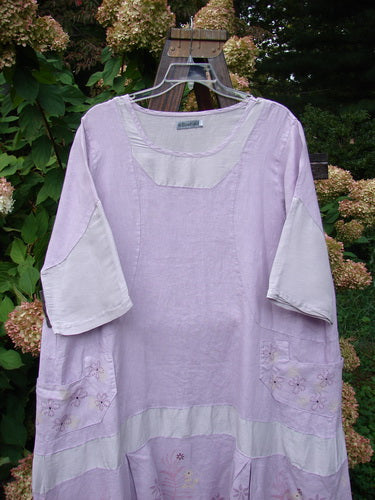 Barclay Linen Contrast Drop Pocket Dress Tiny Flower Heathered Lilac Size 2: A purple shirt with a flower design on it, featuring a beautifully shaped neckline, side drop pockets, and a flutter flounce.