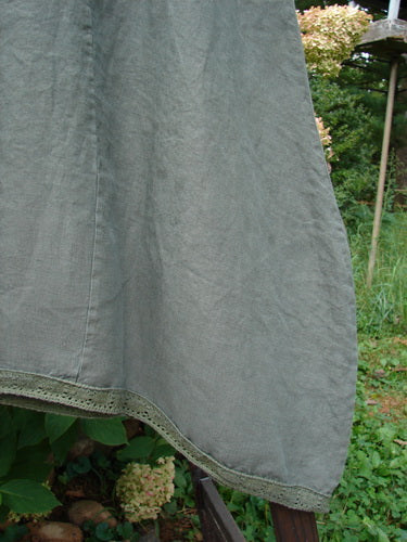 Close-up of the Barclay Linen Lace Blooming Tunic Dress, featuring a cross-over neckline, empire waist, lace-trimmed hem, and scalloped sleeves, showcasing its detailed texture and elegant design.