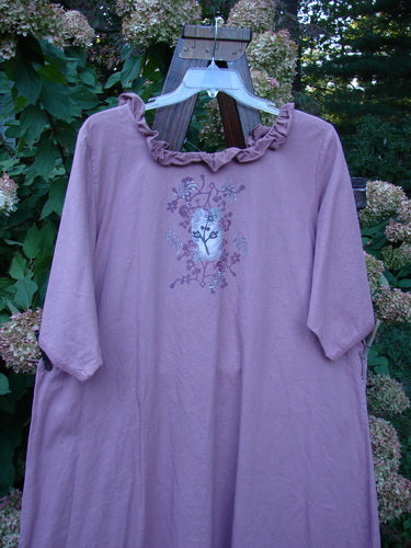 Barclay Linen Duet Sunrise Dress in Dusty Rose, featuring a ruffled neckline and floral motif. The dress has mid-length sleeves, a flared shape, and unique front pockets.