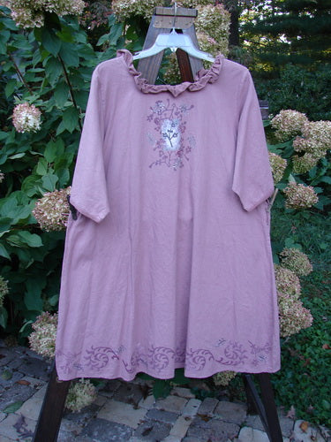 Barclay Linen Duet Sunrise Dress Tiny Floral Dusty Rose Size 2 features a knee-length design with three-quarter sleeves, a ruffled collar, and floral embroidery, hanging outdoors on a wooden rack.