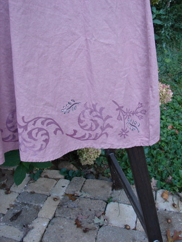Barclay Linen Duet Sunrise Dress in Tiny Floral Dusty Rose Size 2, featuring a scrolling floral hem design on mauve-pink fabric, draped over dark wooden support on a stone patio.