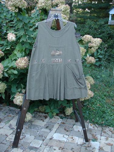 1995 Invention Smock The Garden Snail Bramble OSFA displayed on a rack, showcasing front pleats, a bib pocket, scooped side pockets with metal rivets, and a wide A-line shape.