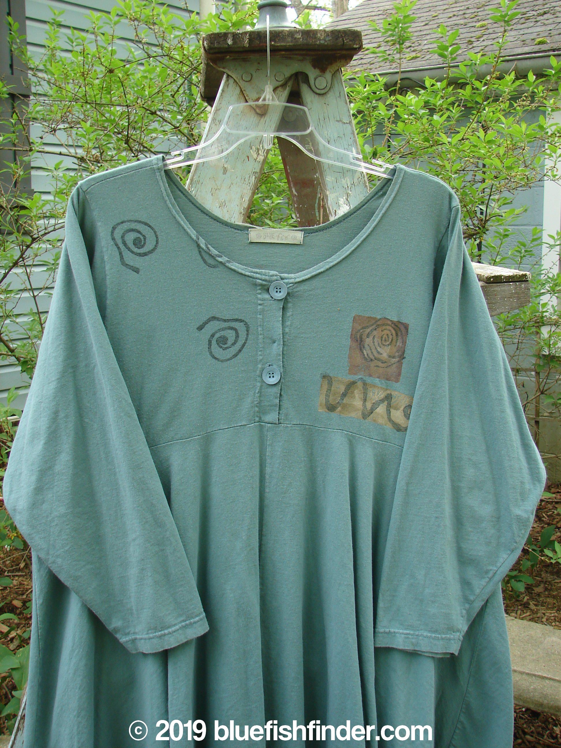 1994 Juniper Dress Swirl Leaf Sea Journey Size 2: A green shirt on a swinger with a plastic swinger on a wooden stand. A drawing of a spiral and a close-up of a drawing. A black spiral on a blue surface. A close-up of a sign, concrete floor, and painting.