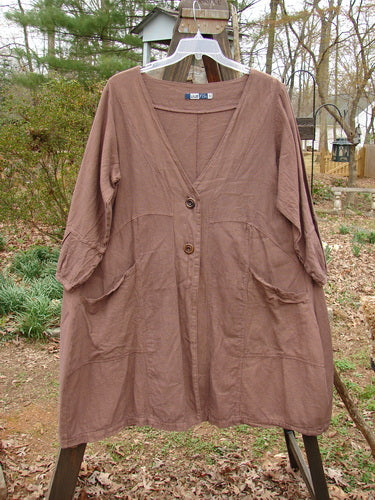 Image alt text: Barclay Linen Adras Uptown Jacket on clothes rack, featuring deep V neckline, pleated lower sleeves and hemline, double drop front pockets, and varying hemline. Size 0, unpainted Redwood.