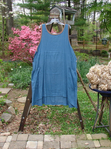 Barclay Linen Contrast Pocket Jumper in Deep Teal, displayed on a clothes rack. Features include a rounded neckline, deeper arm openings, front wrap drop pockets, and an empire waist seam.
