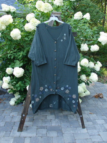 1994 Convertible Coat Spin Flower Deep Moss OSFA showcased on a swing, emphasizing its versatile design with button-on/off sleeves, upward scooped front hemline, and unique flower theme paint.