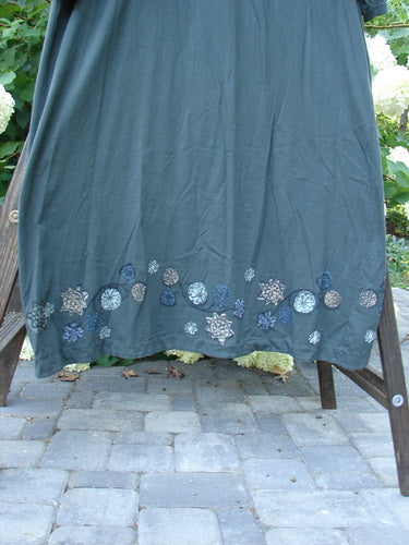 1994 Convertible Coat Spin Flower Deep Moss OSFA featuring button-on/off sleeves, painted flower design, and duster look. Model showcases the coat's scooped hemline and unique drape.