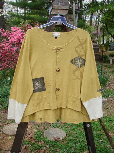 A yellow Philos Jacket with contrasting sleeves, sectional panels, and a gently rounded neckline. Features include a scooped varying hemline, rear flounce, and taganut number buttons. Size 2.