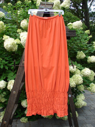 2000 Rings of Saturn Skirt Unpainted Fire Size 2 hanging on a rack, showcasing its full elastic waistline and tapered, pegged lower made from lightweight organic cotton.