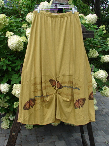 2000 Cotton Hemp Shade Skirt Bio Cell Gold Size 2 featuring butterflies, full elastic waistband, and adjustable hemline, displayed outdoors amidst plants and flowers.