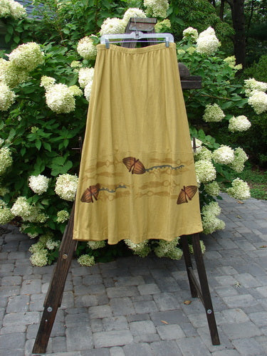 2000 Cotton Hemp Shade Skirt Bio Cell Gold Size 2, featuring a full elastic waistband, varying hemline, and butterfly pattern, displayed on a rack.