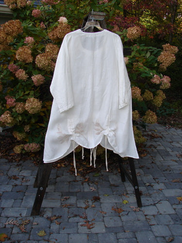 Barclay Linen Venetian High Vent Tunic Dress Tall Bud White Size 2 on a rack, showcasing its flowing mid-weight linen fabric and feminine hourglass shape with unique S-shaped seams and draw cords.