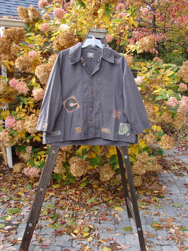 2000 Patched Twill Elio Shirt Iron Size 2 displayed on a wooden hanger, showcasing its oversized wooden buttons, sectional panels with unique stitchery, and classic painted patches.