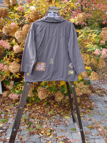 2000 Patched Twill Elio Shirt Iron Size 2 displayed on a stand, showcasing oversized wooden buttons, sectional panels, and painted patches, highlighting its distinctive A-line swing shape and vented sides.