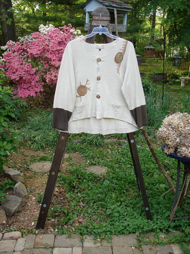 2000 Cotton Hemp Philois Jacket Bio Dove Bark Size 1 displayed on a hanger, featuring brown buttons, a scooped varying hemline, and two lower pockets, highlighting its soft, densely knit fabric.