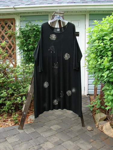 1995 Acetate Lycra Celebration Dress Celtic Turn Onyx Size 2 hanging on a rack, showcasing its flowing sweep, varying hemline, and slightly longer sleeves with a rounded neckline.