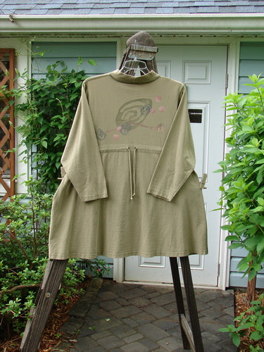 1996 Rambler Dress Follow Path Bottlecap Size 1 displayed on a hanger, showcasing its ribbed mock T-neck, A-line shape, oversized front pocket, adjustable draw cord back, and exterior stitching.