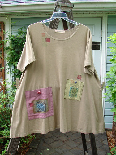 1997 Montage Dress Space Odyssey Wheat Size 2: Tan shirt with patches, featuring oversized exterior front painted pockets, vintage buttons, and a signature Blue Fish patch, medium weight organic cotton.