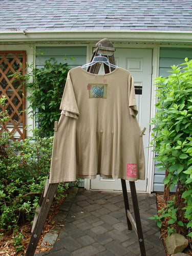 1997 Montage Dress Space Odyssey Wheat Size 2 on a wooden swing, highlighting its A-line shape, offset oversized pockets with vintage buttons, and signature Blue Fish patch.