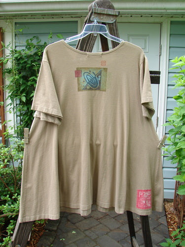 1997 Montage Dress Space Odyssey Wheat Size 2 displayed on a wooden hanger, showcasing its fabulous swingy A-line shape, two oversized painted pockets, and a lovely rounded neckline.