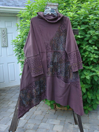 Image alt text: "Barclay Fold Over Collar Puzzle Tunic Dress with floral grid pattern, featuring a purple tunic with a hood on a wooden post, and a purple dress with a patchwork design on a door, from Bluefishfinder.com"