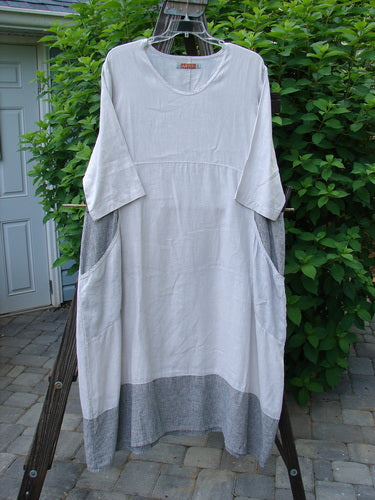 Barclay Linen Stripe Tulip Dress Unpainted Pebble Black Size 1 hanging on a clothesline, showcasing its scoop neckline, three-quarter sleeves, tulip bottom flare, and oversized side pockets.