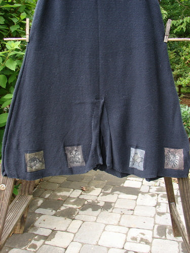 Image alt text: "1994 Vent Vest Sweater Jumper Sea Life Black OSFA: A pair of shorts and a black skirt with patches on a clothesline, showcasing the clothing collection's unique patterns and textures."
