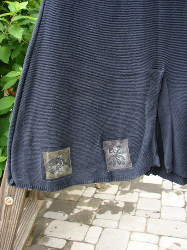 Close-up of the 1994 Vent Vest Sweater Jumper Sea Life Black OSFA, featuring tightly knitted cotton yarns, three clay buttons, and a detailed hemline with whimsical nature paint.