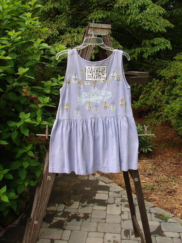 1990 Tiny Tier Top Fish Clover Tiny OSFA featuring a fish design, deep neckline, and bottom flounce, displayed on a swing outdoors amidst greenery.