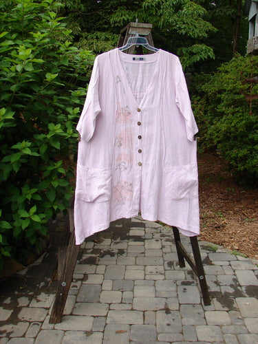 Barclay Linen Double Tie Back Jacket Sprig in Pink Cloud displayed on a clothes rack, showcasing a deep V neckline, front drop pockets, and unique hemline.
