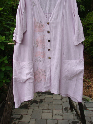 Barclay Linen Double Tie Back Jacket Sprig Pink Cloud Size 0 hanging on a clothesline, showcasing its deep V neckline, A-line sweep, vertical stitchery, front drop-flop pockets, and varying hemline.
