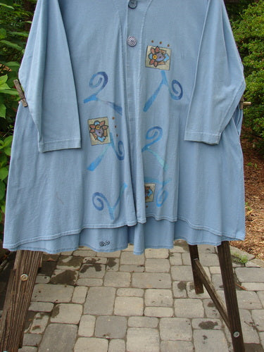 1997 Mask Jacket Windy Floral Peacock Size 1 on a rack, showcasing its bell shape, two-button closure, deep side pockets, and slightly raised draw cord back with a varying rounded hemline.