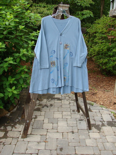 1997 Mask Jacket Windy Floral Peacock Size 1 displayed on a swinger outdoors, showcasing a bell shape, two-button closure, deep side pockets, and a rounded hemline.