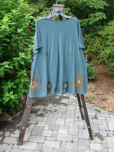 1993 Vagabond Dress Metallic Pinwheel Grey Green OSFA displayed on a hanger outdoors, showcasing its rolled V-shaped neckline and A-line shape with V inserts.
